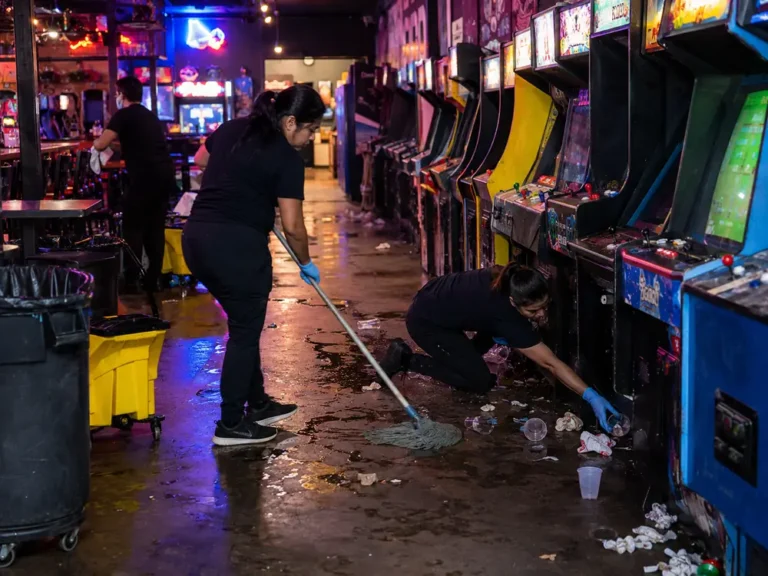 Cleaning crew clearing spills around arcade machines after a Logan Square party
